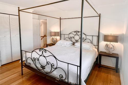 a bedroom with a metal canopy bed with white sheets at Sea La Vie in Virginia Beach