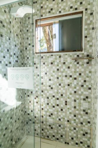 a glass shower with a television in a bathroom at Praia Camburi - Studios Kuta in Camburi