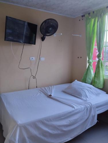 1 dormitorio con 1 cama blanca y TV en la pared en Hotel Indigo en Cartago