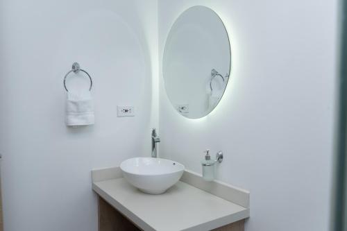 Baño blanco con lavabo y espejo en NOVO Hotel Boutique, en Ríohacha