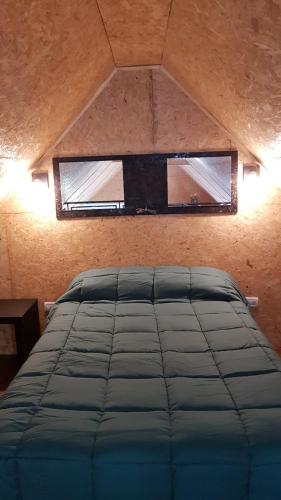 a bed in a room with a window above it at La Cappella Casa Quincho in Sierra de los Padres