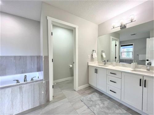 a white bathroom with two sinks and a large mirror at Luxury Retreat For Large Groups in Calgary
