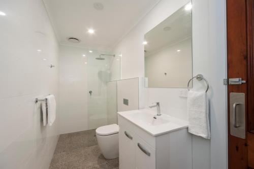 a white bathroom with a toilet and a sink at Barossa Brauhaus Hotel in Angaston