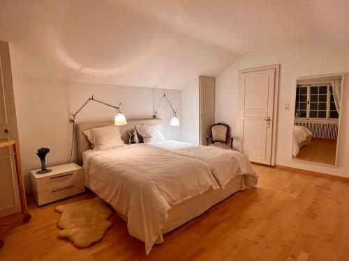 um quarto com uma grande cama branca e piso em madeira em Le Cottage em Vésenaz