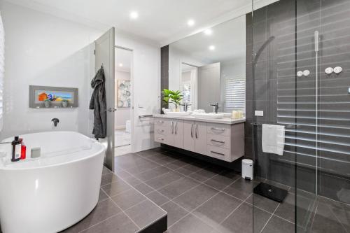 łazienka z wanną, 2 umywalkami i prysznicem w obiekcie Craigie’s Hut – Luxury Accommodation on the Mornington Peninsula w mieście Mount Martha