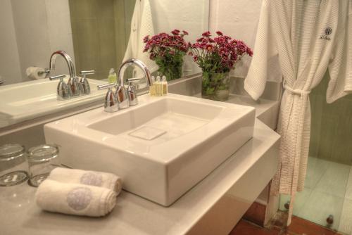 a white sink in a bathroom with flowers on a counter at Alta Las Palomas Hotel in San José