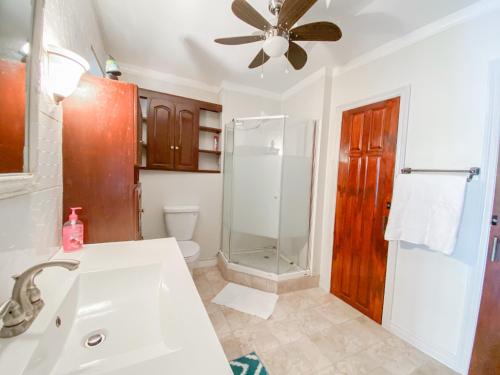 uma casa de banho com um chuveiro e um lavatório branco em Paradise Villa em Port Elizabeth
