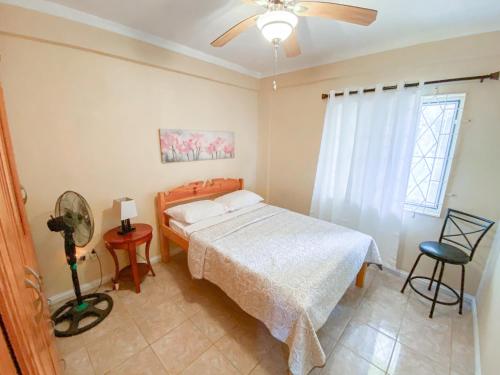 a bedroom with a bed and a fan and a window at Paradise Villa in Port Elizabeth