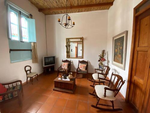 een woonkamer met stoelen en een tafel en een televisie bij Mi casita “Chinco” estrellas in Zapatoca