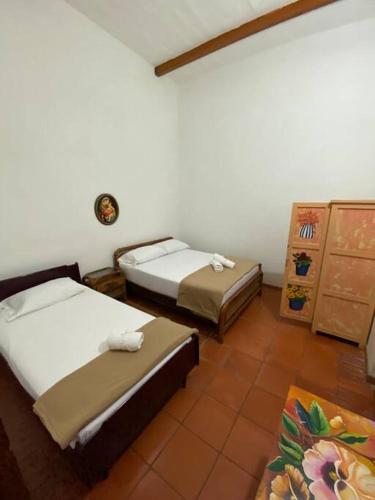 a room with two beds and a dresser at Mi casita “Chinco” estrellas in Zapatoca