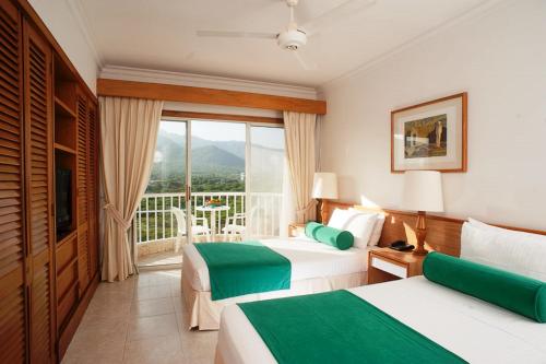 a hotel room with two beds and a balcony at Irotama Apartasuites in Santa Marta