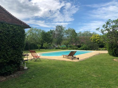 una piscina con due sedie e un tavolo di Gîte charmant avec piscine chauffée, tennis et jardin près de Beaumont-sur-Sarthe - FR-1-410-214 a Maresché