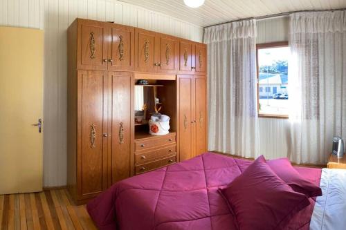 a bedroom with a purple bed and wooden cabinets at Casa aconchegante no Vale Vinhedos in Bento Gonçalves