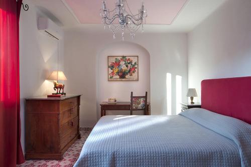 a bedroom with a bed and a dresser and a chandelier at Villa Gianturco - Luxury In The Green Island in Ischia