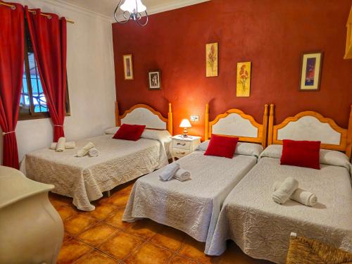 two beds in a room with red walls at JARANDALUS (casa con atractivo y encanto) in El Gastor