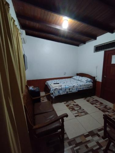 ein Schlafzimmer mit einem Bett und Stühlen in einem Zimmer in der Unterkunft LAS ORQUIDEAS Hospedaje in Pucallpa