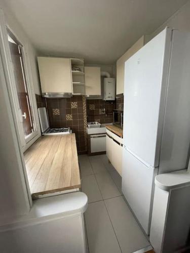 a kitchen with a white refrigerator and a wooden counter top at Super appartement à vitry-sur-seine in Vitry-sur-Seine