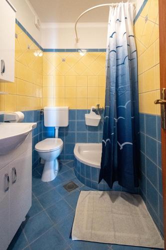 a blue and yellow bathroom with a toilet and a sink at Apartments by the sea Mandre, Pag - 4092 in Kolan