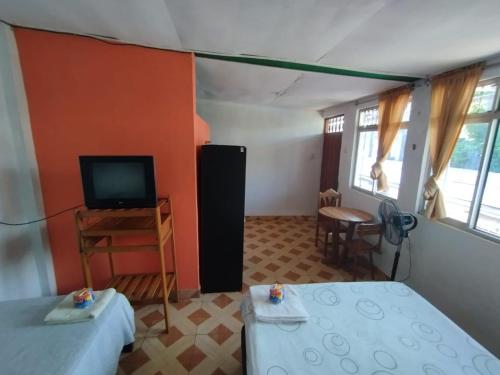 een kamer met 2 bedden, een televisie en een tafel bij LAS ORQUIDEAS Hospedaje in Pucallpa