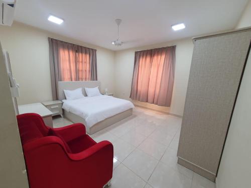 a bedroom with a white bed and a red chair at Terhal salalah 1 in Salalah