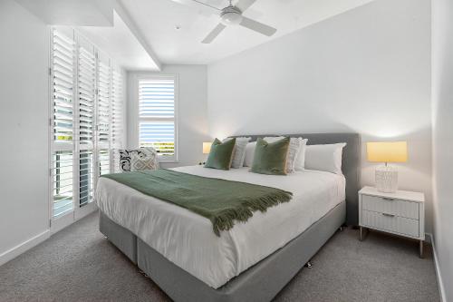 a white bedroom with a large bed and windows at Oceanus Bokarina Beach in Kawana Waters