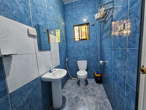 Baño de azulejos azules con aseo y lavamanos en LaCasita 2BD Home with Starlink en Catarman