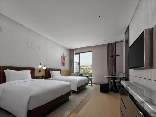 a hotel room with two beds and a flat screen tv at DoubleTree By Hilton Cangnan in Cangnan