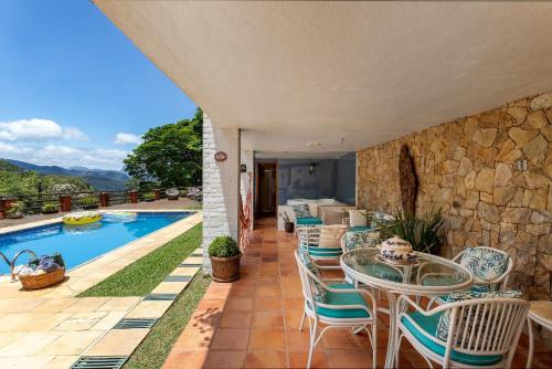 um pátio com uma mesa e cadeiras ao lado de uma piscina em Casa em Araras: Piscina, sauna e serviço incluído! em Araras, Petrópolis