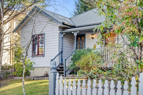 una casa blanca con una valla blanca en Whispering Pines Cottages en Wentworth Falls