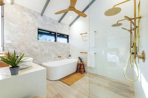 a bathroom with a tub and a glass shower at 'Villa Nalu' A Dreamy Fannie Bay Escape in Fannie Bay