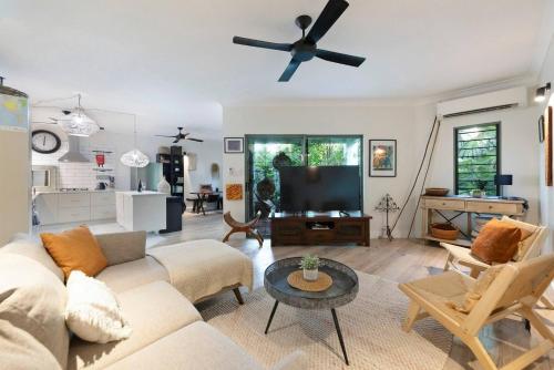 a living room with a couch and a ceiling fan at Where Enchanted Garden meets Tropical Paradise in Darwin