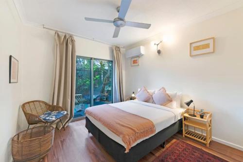 - une chambre avec un lit, un ventilateur de plafond et une fenêtre dans l'établissement The Enchanted Garden - Breezy Tropical Allure, à Darwin