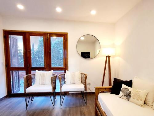 Una sala de estar con un sofá y un espejo. en Duplex BESUGO, con patio y parrilla, en Pinamar