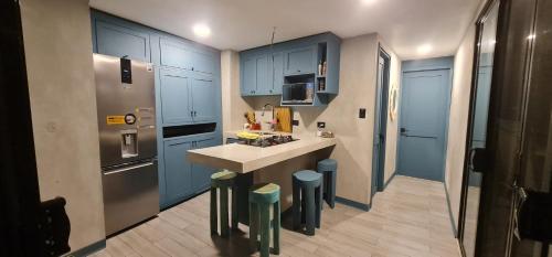 eine Küche mit blauen Schränken und eine Kücheninsel mit Hockern in der Unterkunft LA CABAÑA & hiking in Jacó