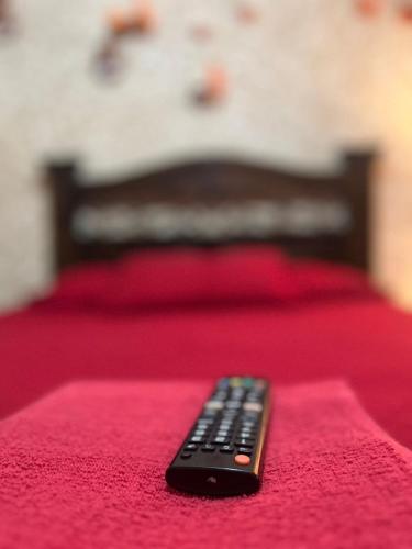 a remote control sitting on top of a red bed at Cristales de Antigua Hotel Cristal in Antigua Guatemala