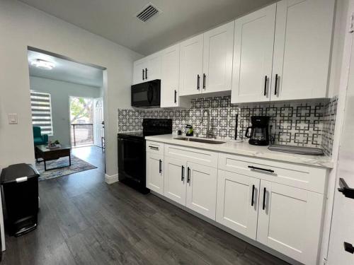 una cocina con armarios blancos y electrodomésticos negros en Stylish 2/1 centrally located! en Miami