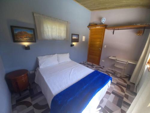 um quarto com uma cama com um cobertor azul e branco em Casinha acolhedora da mata - Rota do Vinho em São Roque