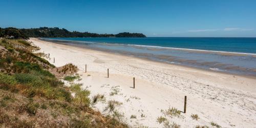 a beach with a fence in the sand and the ocean at Onetangi Beach Stays Apartment - Coast & Country in Onetangi
