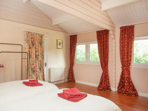 two beds in a bedroom with red curtains at 2 The Follys - Uk45188 in Abbotskerswell
