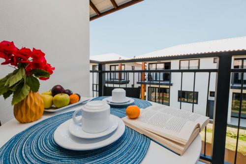 uma mesa com um livro e algumas frutas na varanda em Eita Bahia em Praia do Forte