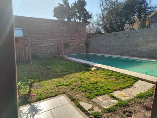 un patio trasero con piscina y pared de ladrillo en Hostel Bauti en Ezeiza en Ezeiza