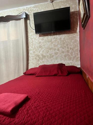 a bedroom with a red bed with a flat screen tv on the wall at Cristales de Antigua Hotel Cristal in Antigua Guatemala