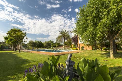 a garden with a swimming pool and trees at Hotel Sausa in Vilafreser