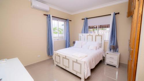 a bedroom with a white bed and blue curtains at Sky Blue in Jarabacoa