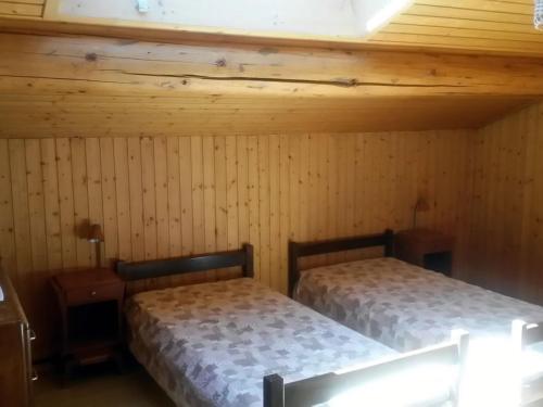 deux lits dans une chambre aux murs en bois dans l'établissement Chalet spacieux 12 pers, proche pistes et navette, parking privé - FR-1-467-121, au Grand-Bornand