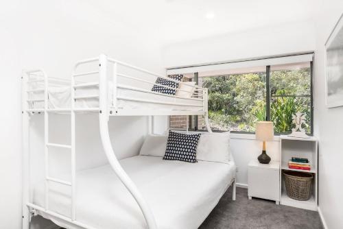 a white bunk bed in a white room with a window at A Perfect Stay - 11 James Cook Apartments in Byron Bay