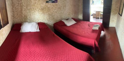 two beds in a room with red sheets at Cristales de Antigua Hotel Cristal in Antigua Guatemala
