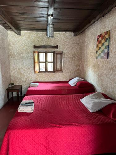 two beds in a room with red sheets at Cristales de Antigua Hotel Cristal in Antigua Guatemala