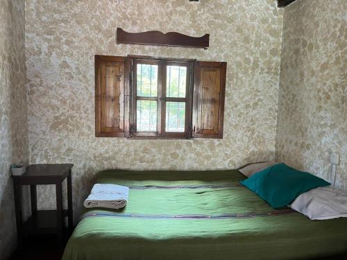 a bedroom with a green bed with a window at Cristales de Antigua Hotel Cristal in Antigua Guatemala