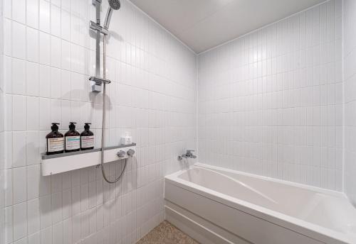 un bagno bianco con vasca e lavandino di Browndot Hotel Yeosu Yeocheon a Yeosu